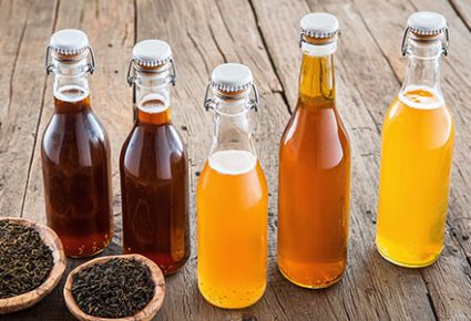 a rustic wooden table displaying various stages of kombucha brew